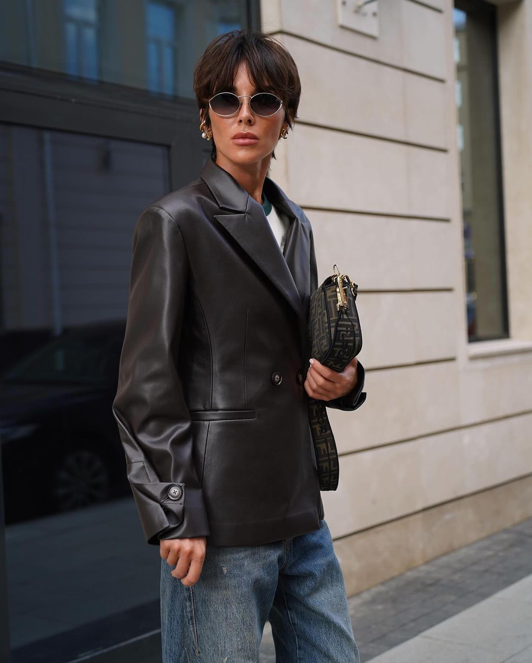 Black collared leather jacket over a classic blue button-up shirt